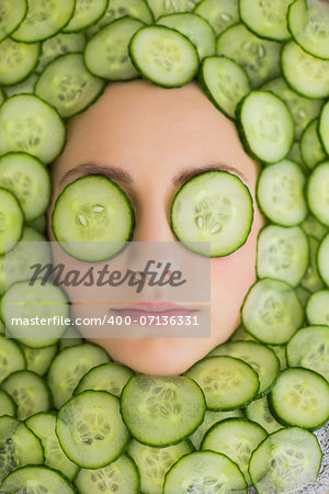 Close up of a young beautiful woman with facial mask of cucumber slices on her face at spa salon