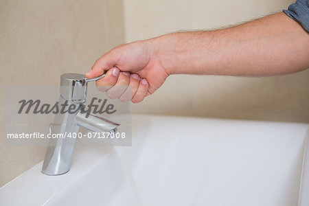 Extreme Close up of a plumber's hand opening a water tap at bathroom