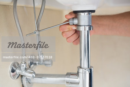 Extreme Close up of a plumber's hand and washbasin drain at bathroom