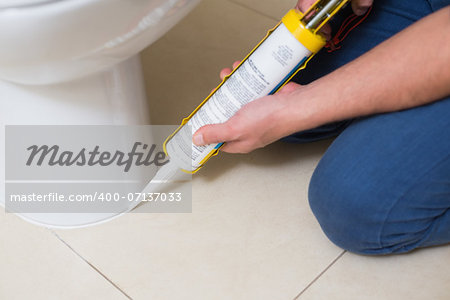 Close up of a plumber fixing toilet in a washroom with silicone cartridge