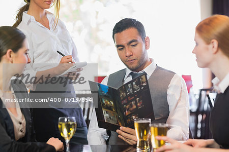 Handsome businessman ordering dinner from waitress in a restaurant