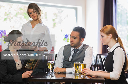 Three business people ordering a dinner in restaurant from waitress