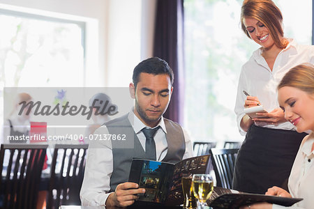 Two business people ordering dinner from waitress in restaurant