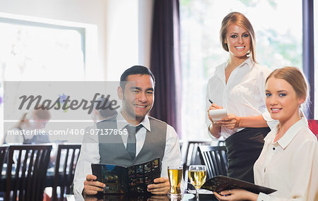 Business people and waitress smiling at camera in restaurant