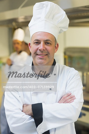 Proud mature chef posing in a kitchen with crossed arms