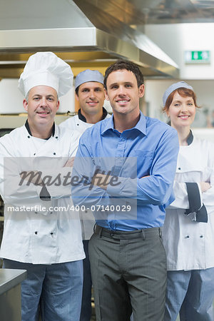 Handsome manager posing with some chefs in a kitchen