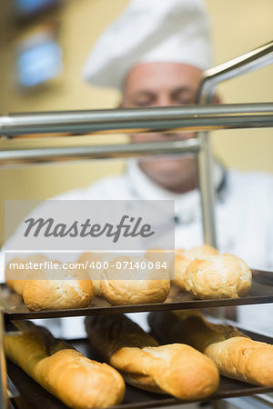 Mature baker pushing a trolley with baguettes on it