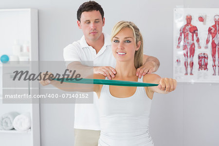 Handsome physiotherapist correcting position of patient in bright office