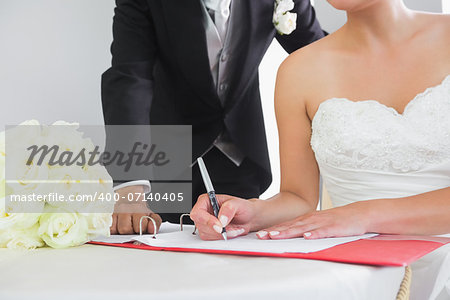 Mid section of a young couple signing wedding contract sitting at desk