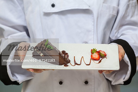 Chef presenting chocolate cake with strawberries on white plate