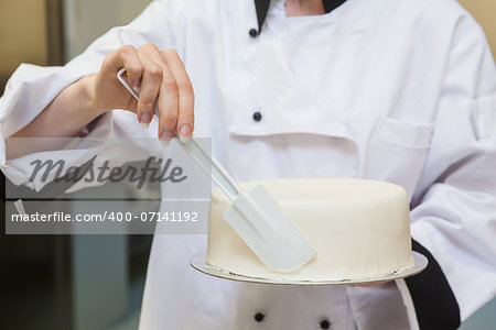 Chef finishing a cake with icing in professional kitchen