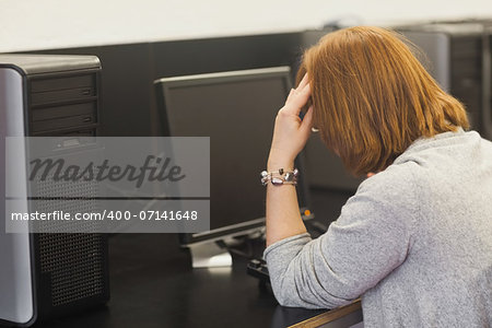 Annoyed female mature student working on computer in computer room