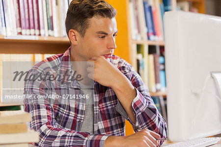 Handsome serious student using computer in library