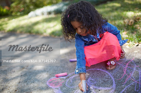 Girl drawing with chalk on the sidewalk