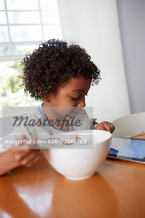 Boy eating breakfast and using digital tablet