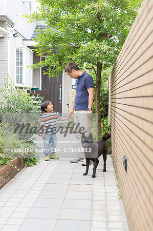 Father and young son on path with dog