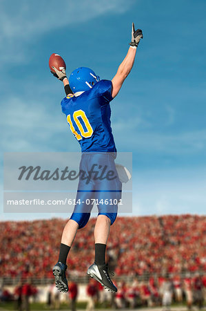 American footballer jumping with ball