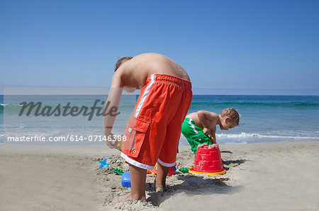 Two young brothers building sandcastles on beach