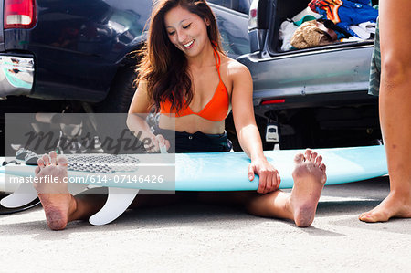 Woman sitting with surfboard, Hermosa Beach, California, USA