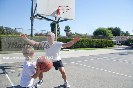 Boy and grandfather playing basketball