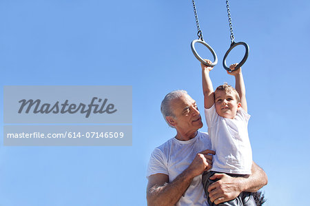 Grandfather holding grandson on gymnastic rings