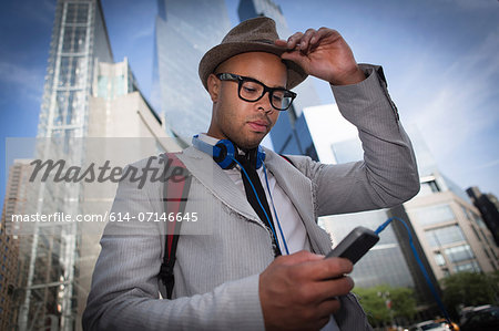 Young man wearing hat and glasses using mp3 player