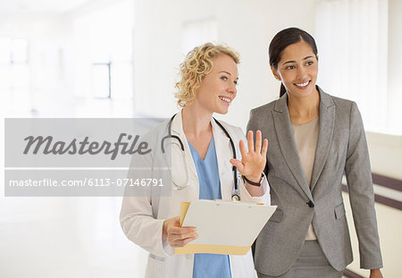 Doctor and businesswoman talking in hospital corridor