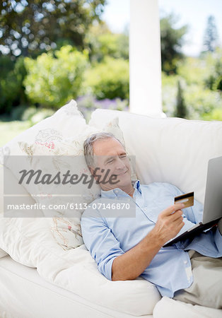 Senior man shopping online on patio sofa