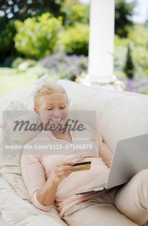 Senior woman shopping online on patio sofa