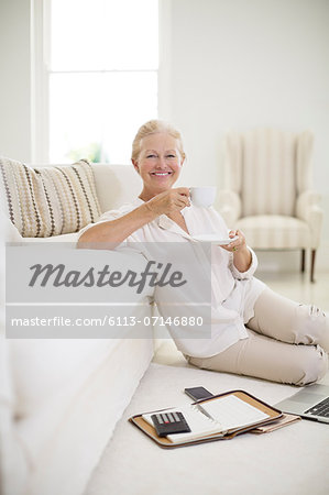 Senior woman drinking coffee on living room floor