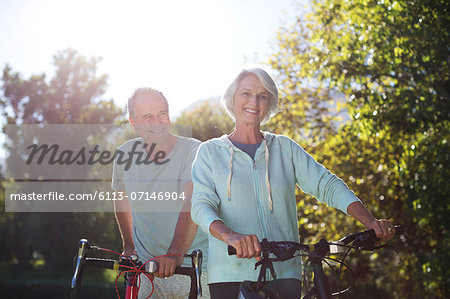 Senior couple walking bicycles in park