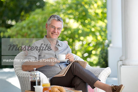 Portrait of smiling senior man drinking coffee on patio
