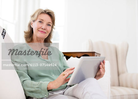 Portrait of senior woman using digital tablet on sofa