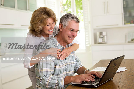 Senior couple using laptop in kitchen