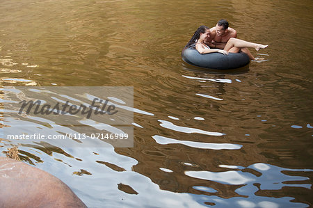 Couple playing in inner tube in lake