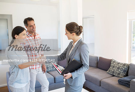 Realtor and couple handshaking in living room Realtor and couple handshaking in living room