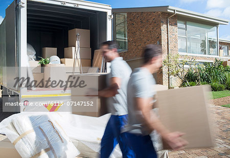 Movers carrying cardboard boxes in driveway