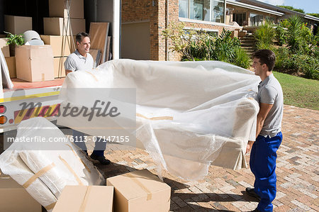 Movers carrying sofa from moving van in driveway