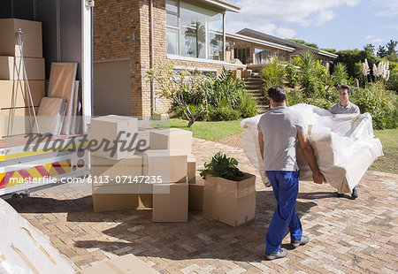 Movers carrying sofa from moving van to house