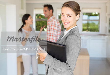 Portrait of smiling realtor with couple in background