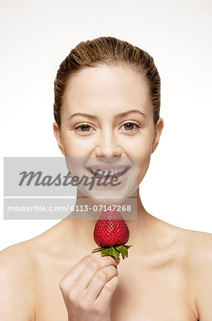 Smiling woman eating strawberry