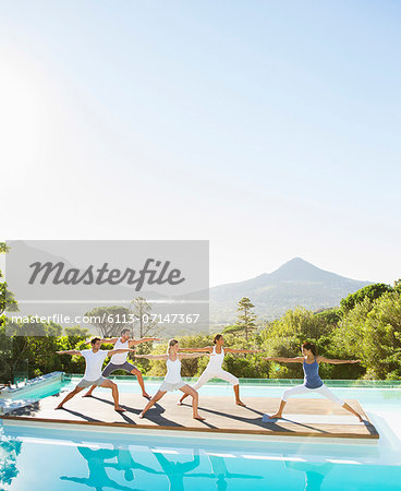 People practicing yoga at poolside