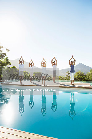 People practicing yoga at poolside