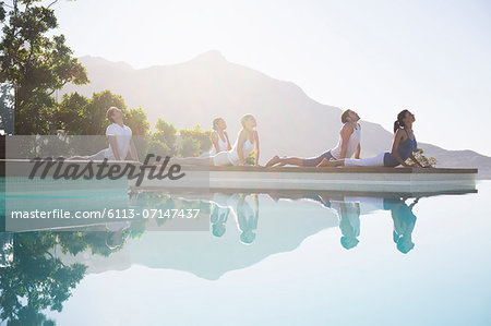 People practicing yoga at poolside