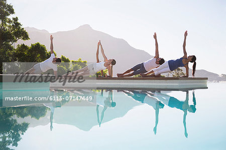 People practicing yoga at poolside