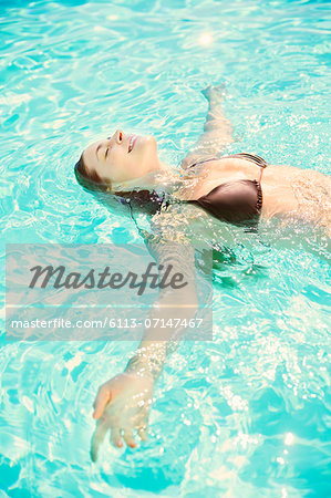 Woman relaxing on back in swimming pool