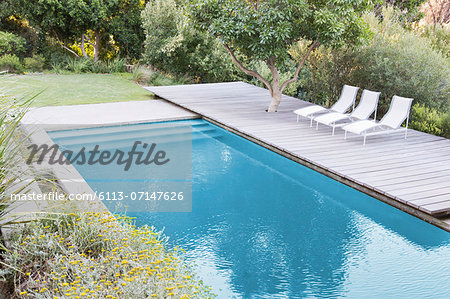 Wooden deck and lounge chairs by swimming pool