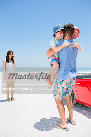 Father hugging children on beach