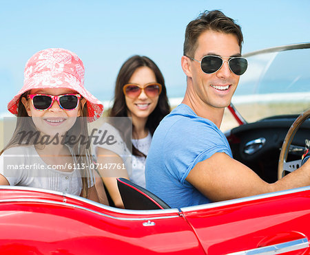 Family driving in convertible on beach