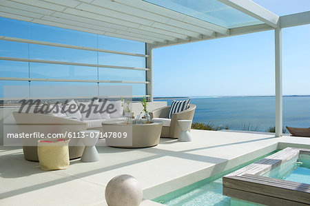 Sofa and chairs by swimming pool overlooking ocean